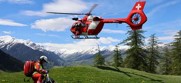 Un hélicoptère de sauvetage transporte un patient jusqu’à l’hôpital le plus proche. Pendant ce temps, un médecin d’urgence de la Rega attend et range du matériel.