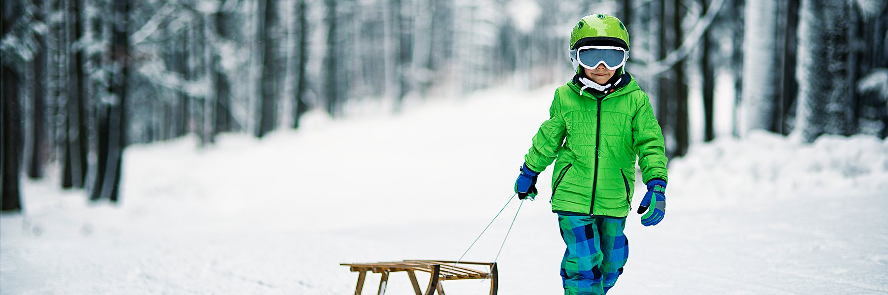 Kind mit Schlitten im Schnee