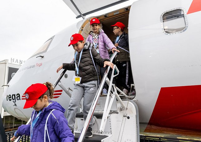 Les enfants quittent l’avion de la Rega par les escaliers 