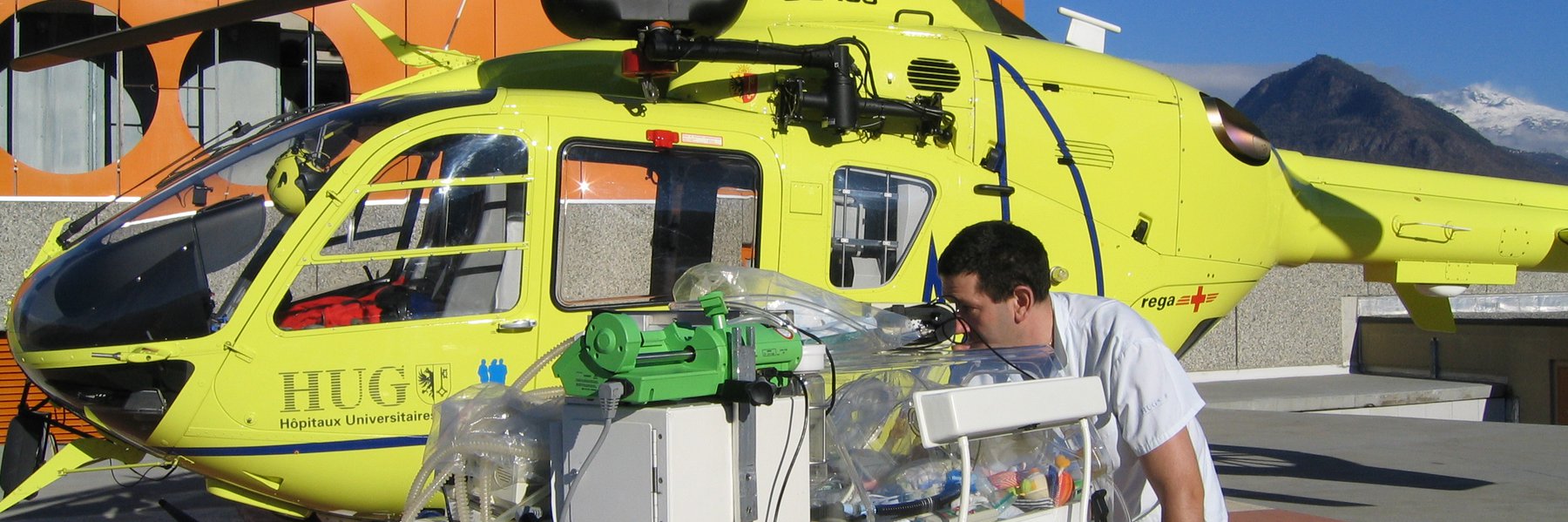 Photo symbole : L’isolette de transport et l’EC-135 de la base Rega-HUG de Genève (crédit photo HUG)