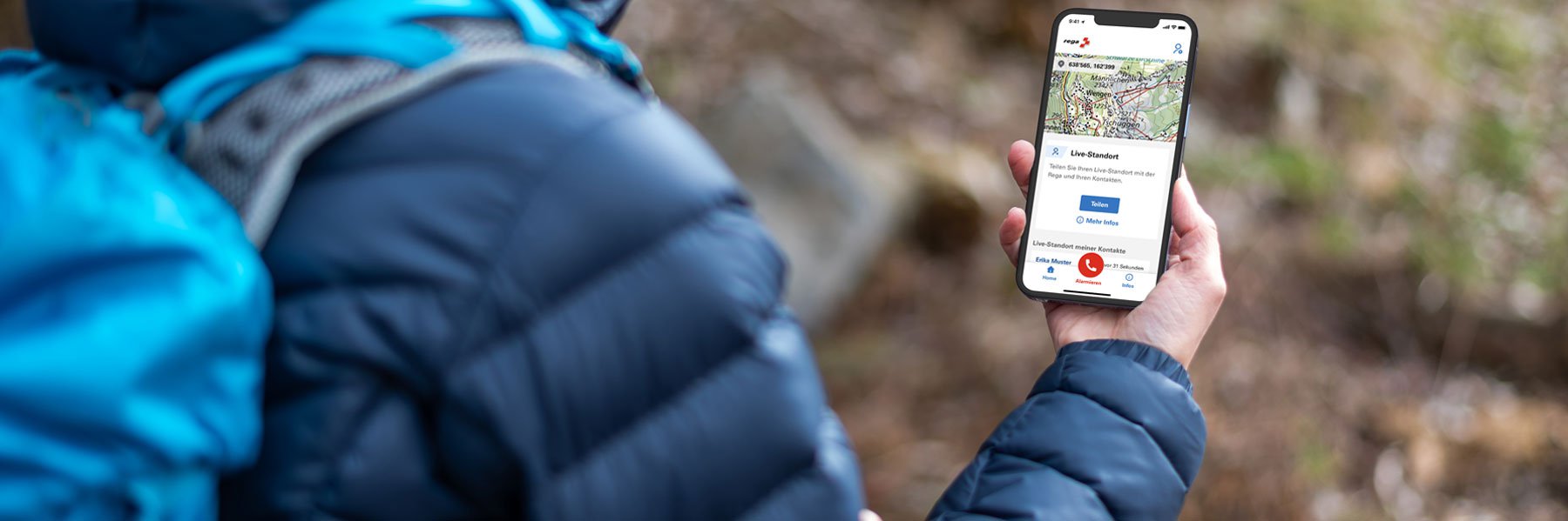 Wanderin hält ein Handy auf dem die Rega-App geöffnet ist.