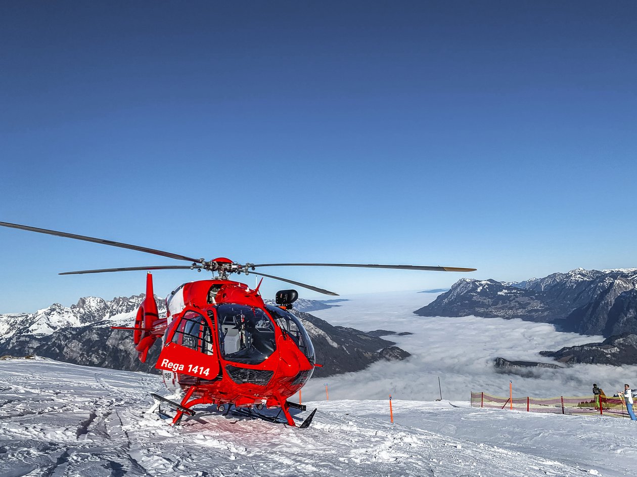 Hélicoptère de sauvetage sur une piste de ski avec un plafond nuageux en arrière-plan
